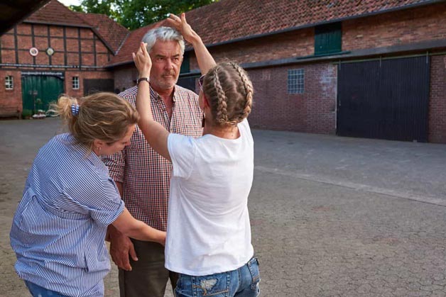 Visagistin bereitet männliches Model für Aufnahmen vor - Windrich & Sörgel